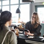 Woman using credit card at restuarant