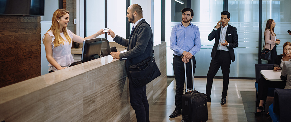 Business travelers using credit card at hotel reception